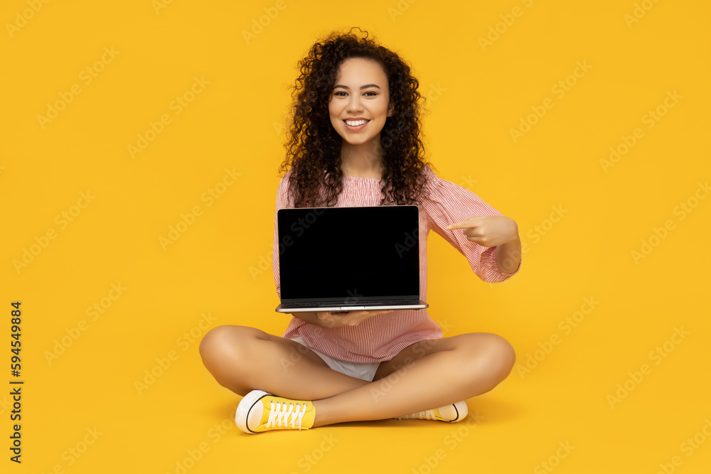 Naklejka premium Young woman with laptop on yellow background