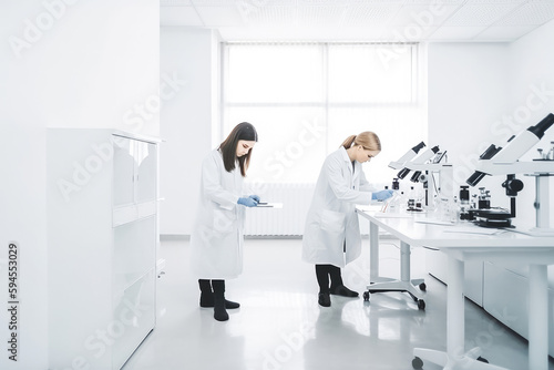 Professional smart women working in the laboratory looking at samples through microscope. Doing analysis and working. Generative AI.