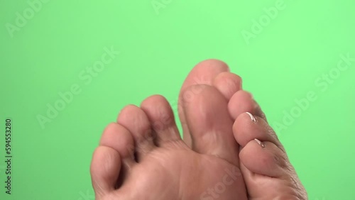 Close-up of the bottom of wrinkled toes wiggling in front of a green chroma key background. photo