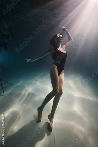 Fototapeta Naklejka Na Ścianę i Meble -  A girl in a mask underwater in the pool in the water