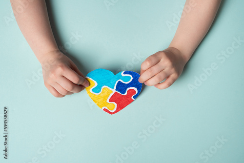 Wallpaper Mural Child hands holding colorful puzzle heart on blue background. Multi-colored heart as a symbol of World Autism Awareness Day Torontodigital.ca