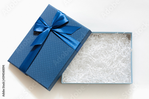 Open gift box with shredded paper on a white background. Blue cardboard box with decorative fillers for your product. Flat lay, top view, empty space for products photo