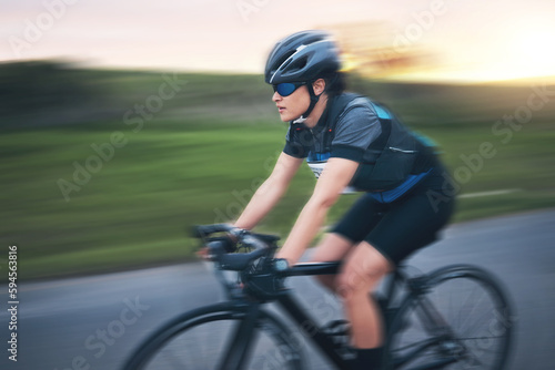 Motion blur, fitness and cycling woman on road for training, competition and nature championship. Workout, sports and triathlon with female cyclist on bike for freedom, exercise and fast speed