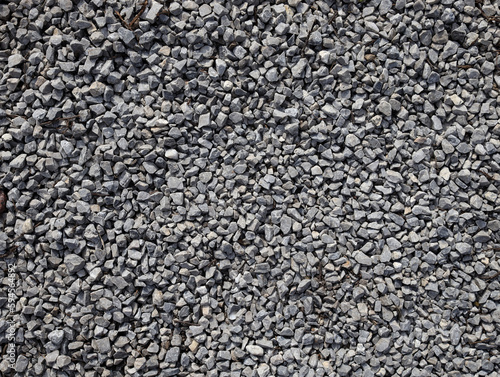 Gray stone gravel texture background. Broken stone or crushed rock texture with place for text. dark background of crushed granite gravel, close up top view.