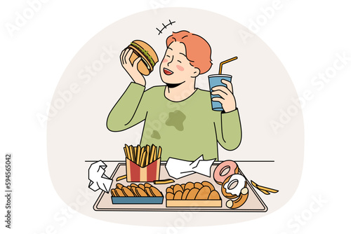 Unhealthy eating in childhood concept. Smiling cheerful fatty boy sitting and eating hamburger donuts french fries drinking lemonade enjoying junk food vector illustration