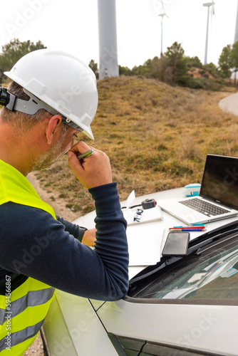 electrical engineer thinking and blueprint of wind turbine for maintenance of windmill in wind farm
