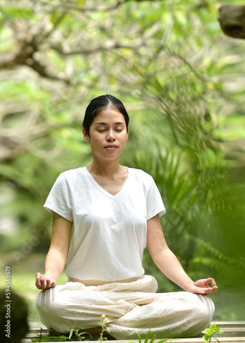 Asian woman meditating in the woods. Forest yoga. Mindfulness.