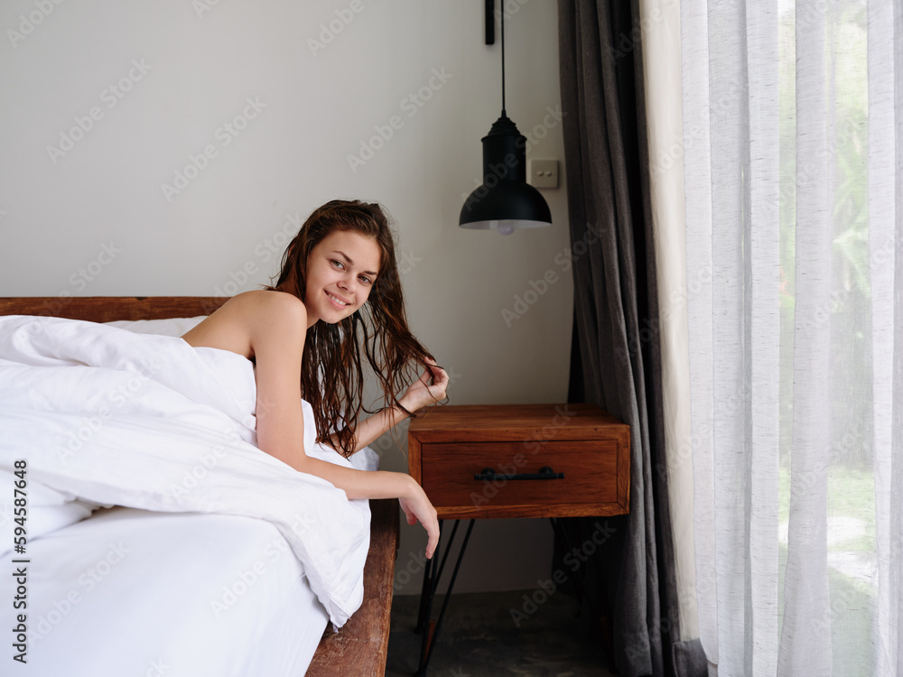 A woman after a shower lies on a bed in a bedroom near a window with wet hair, a healthy sleep on an orthopedic patras and a memory foam pillow, body and hair care A woman after a shower lies on a bed in a bedroom near a window with wet hair, a healthy sleep on an orthopedic patras and a memory foam pillow, body and hair care