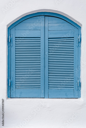 Closed blue wooden shutters on a white painted house facade in mediterranean architectural style
