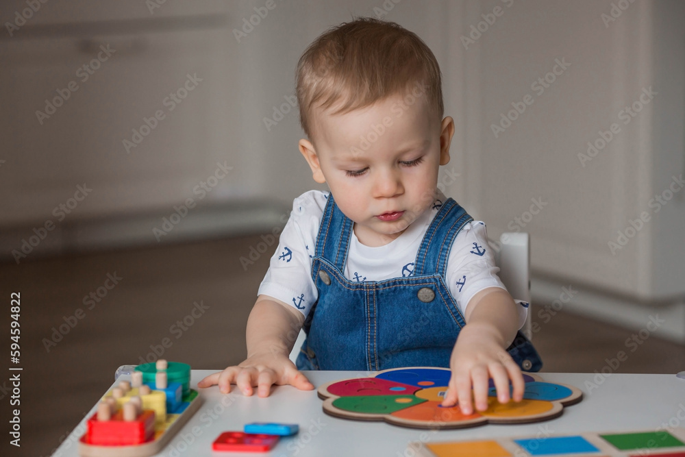 A little boy is playing educational logic games. Children's wooden toys. Sorter. Montessori for child development. A little boy is playing educational logic games. Children's wooden toys. Sorter. Montessori for child development.