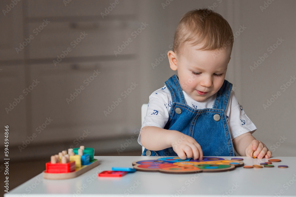 A little boy is playing educational logic games. Children's wooden toys. Sorter. Montessori for child development. A little boy is playing educational logic games. Children's wooden toys. Sorter. Montessori for child development.