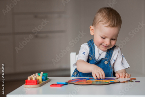 A little boy is playing educational logic games. Children's wooden toys. Sorter. Montessori for child development.