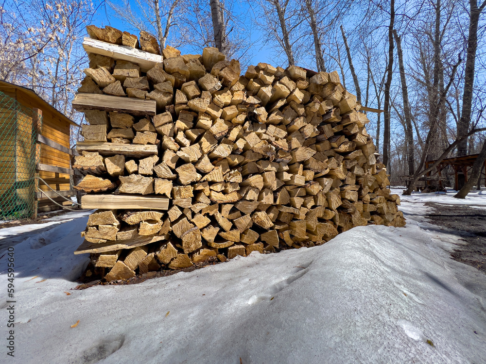 Neatly stacked firewood for the stove is lying in the park. Soft focus