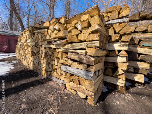 Neatly stacked firewood for the stove is lying in the park. Soft focus