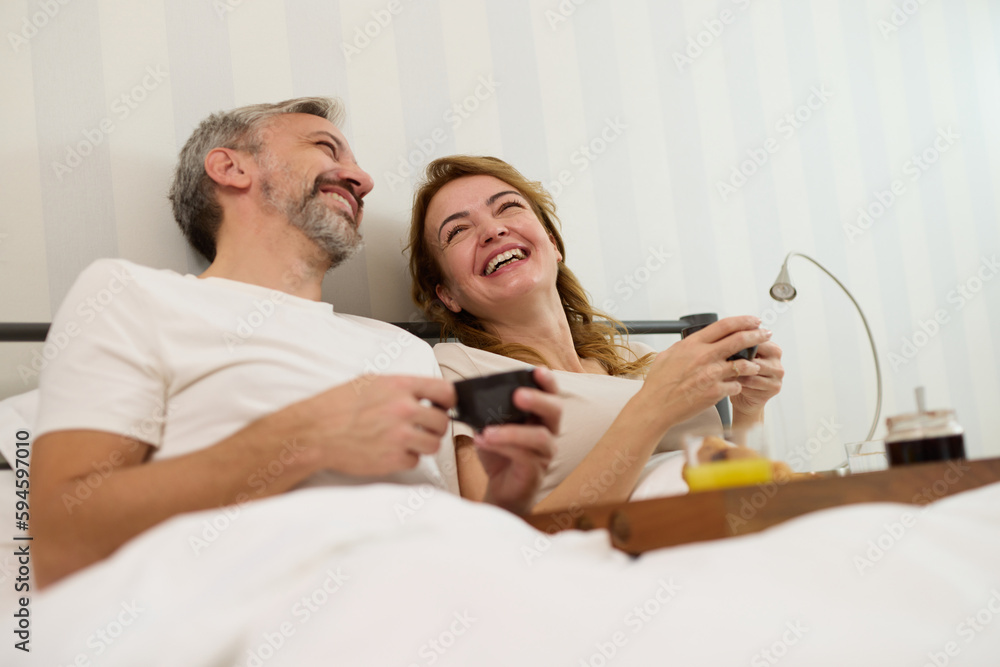 Mature couple enjoying coffee and breakfast at home.in bed Mature couple enjoying coffee and breakfast at home.in bed