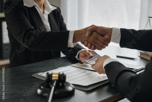Businesswoman, investor shaking hands and giving bribe to lawyer to help win court case with documents to sign agreement The concept of bribery and money delivery on the table. Fraud