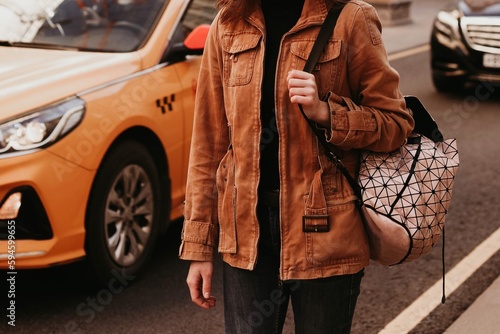 Young woman in stylish brown denim autumn fashionable jacket and black jeans. Street style casual fashion details photo