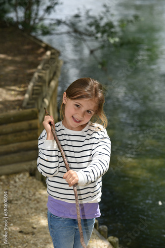 smiling young girl with a marinière and a stick in front of a river
