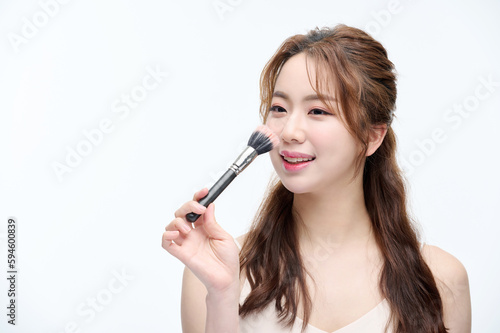 Beautiful Young Asian woman with clean fresh skin touching two hands on face in beauty pose. Pretty girl smiling in white background. cosmetology, make up concept with several brushes