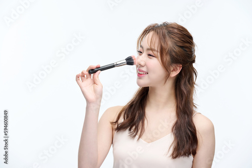 Beautiful Young Asian woman with clean fresh skin touching two hands on face in beauty pose. Pretty girl smiling in white background. cosmetology, make up concept with several brushes