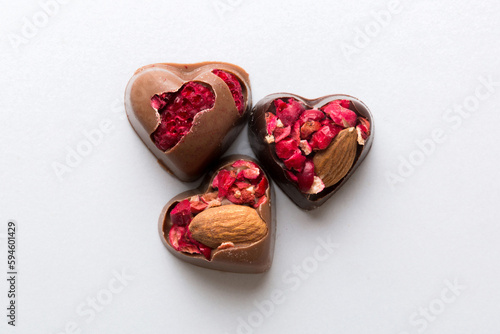 chocolate sweets in the form of a heart with fruits and nuts on a colored background. top view with space for text, holiday concept © sosiukin