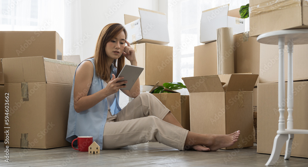 Moving house, mortgage, family and real estate concept. Asian young woman inspecting quality stuff in boxes with digital tablet while moving into new house. Woman checking stuff in cardboard boxes Moving house, mortgage, family and real estate concept. Asian young woman inspecting quality stuff in boxes with digital tablet while moving into new house. Woman checking stuff in cardboard boxes