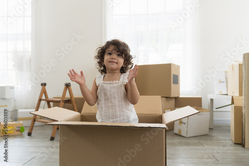 Moving house, mortgage, family and real estate concept. Happy cute little daughter baby toddler girl playing inside of cardboard box family moving into new house © amorn