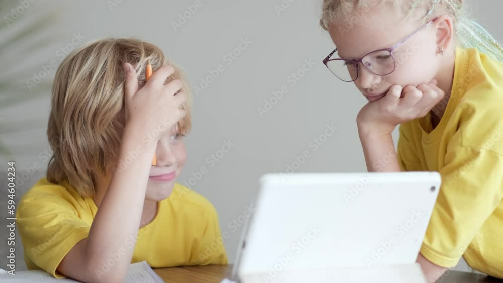 Sister helps little brother do school homework at home, Distance learning online education, boy and girl studying at home with digital tablet. Sister helps little brother do school homework at home, Distance learning online education, boy and girl studying at home with digital tablet.