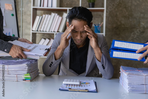 Young accountant stressed out overloaded with paperwork with colleague handing over documents