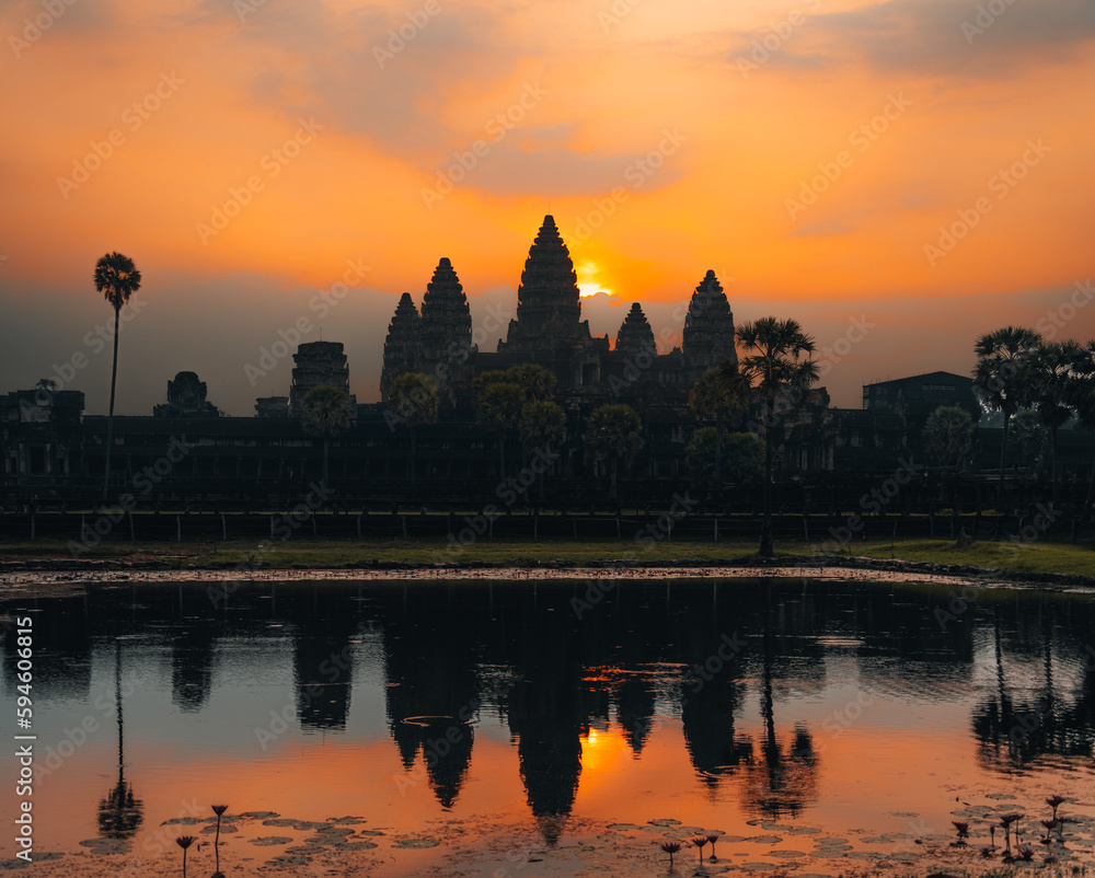 Angkor Wat in Cambodia during sunrise with palms.