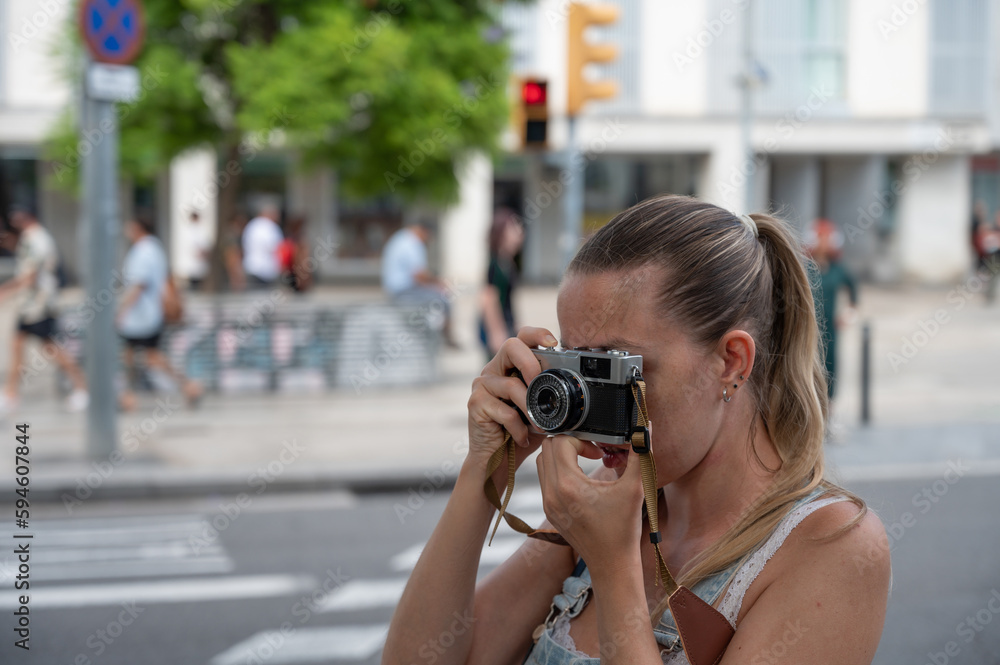 Portrait of a young blonde girl with a ponytail taking photos with her analog travel camera
