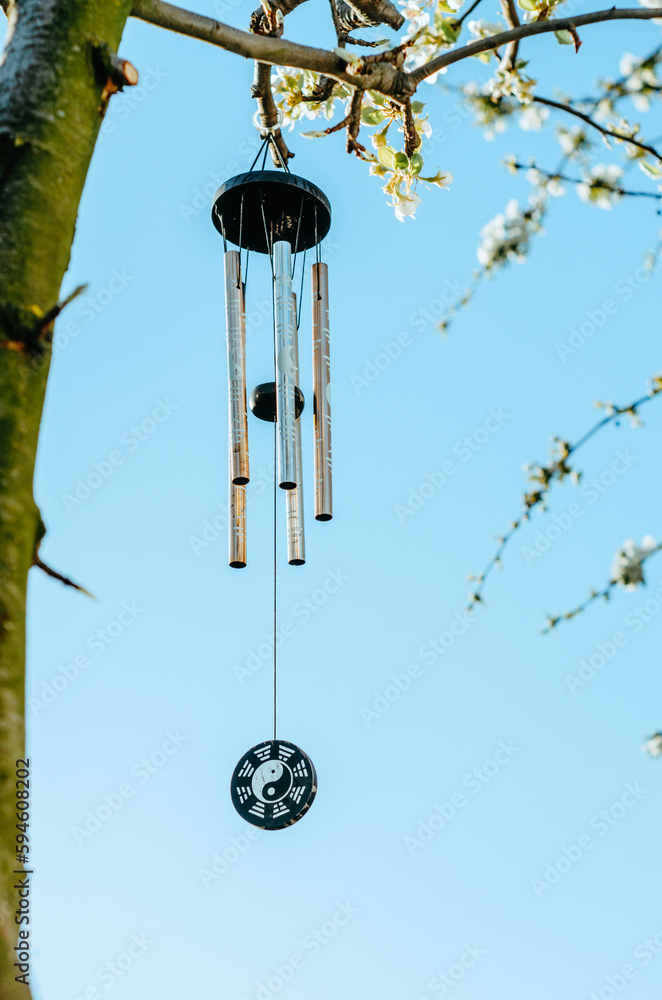 Wind chime with zen symbolism hanging on tree in blossom with sky ...