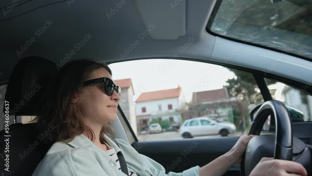 A young Caucasian woman in sunglasses driving a car, view from the inside of the car. A young Caucasian woman in sunglasses driving a car, view from the inside of the car.