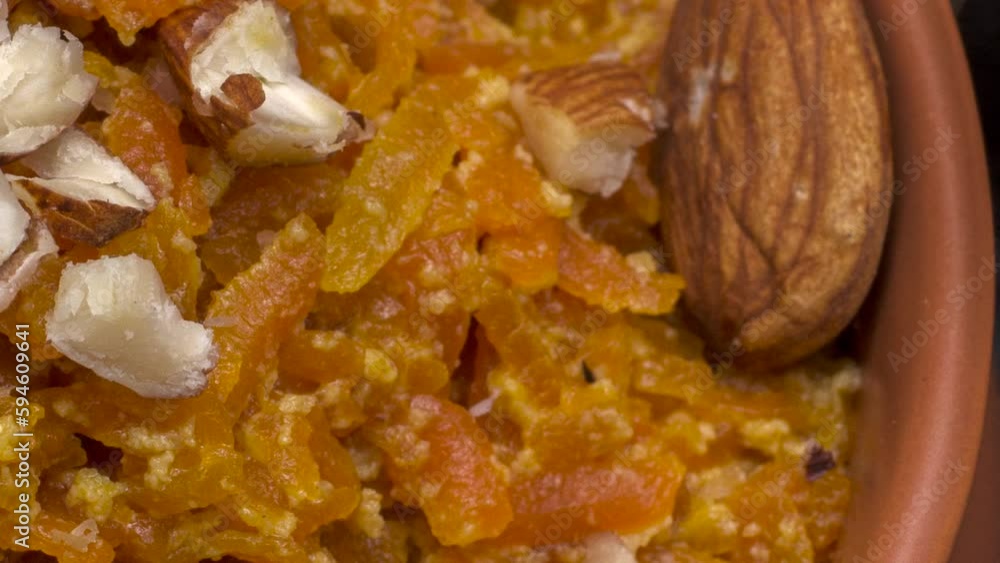Gajar ka halwa is a carrot based sweet dessert from India. Garnished with Cashew and almond nuts and Served in a bowl over black background. Selective focus.