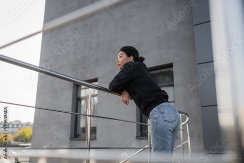 Canvas Print Side view of sad multiracial woman with apathy standing near railing on urban street