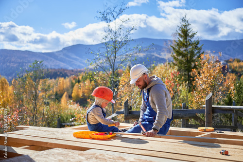 Father with toddler son building wooden frame house Fototapet