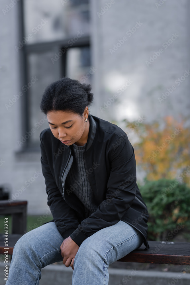 Sad multiracial woman with mental problem sitting on bench on urban street. Sad multiracial woman with mental problem sitting on bench on urban street.