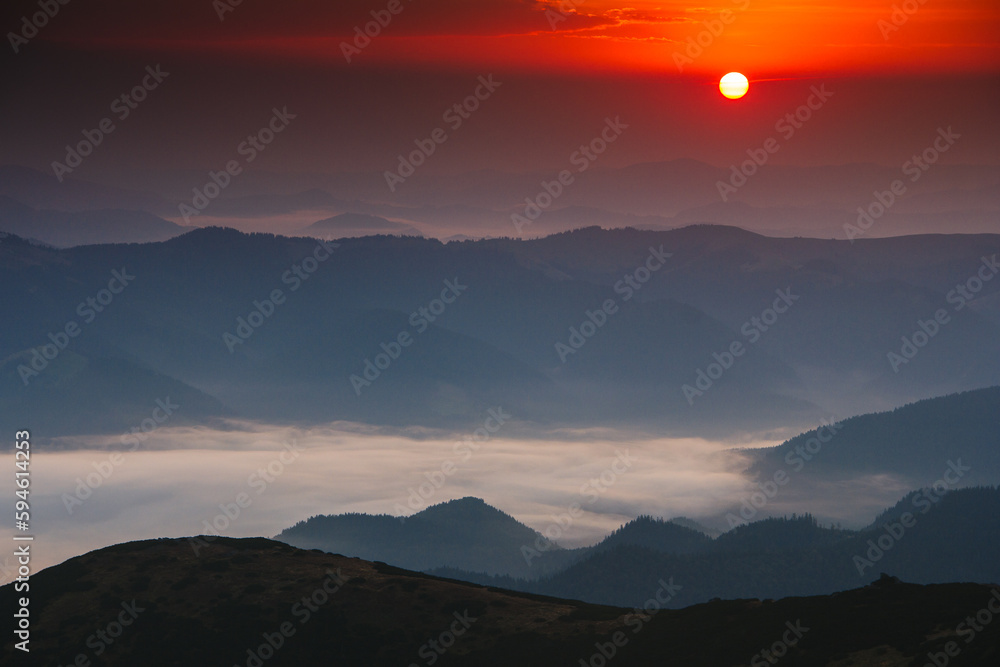 Beautiful landscape in the mountains at sunrise. Fog in the valley. View of a mountain valley in a  early morning with fog between hills.