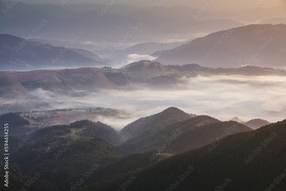View of a mountains valley in a  early morning with fog between hills.