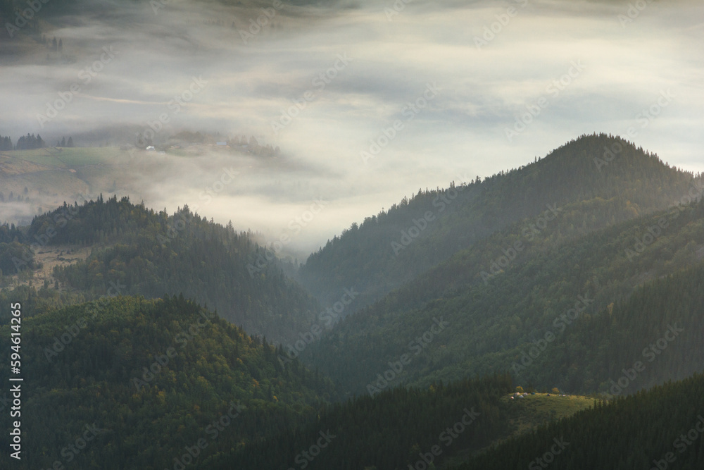 View of a mountains valley in a  early morning with fog between hills.