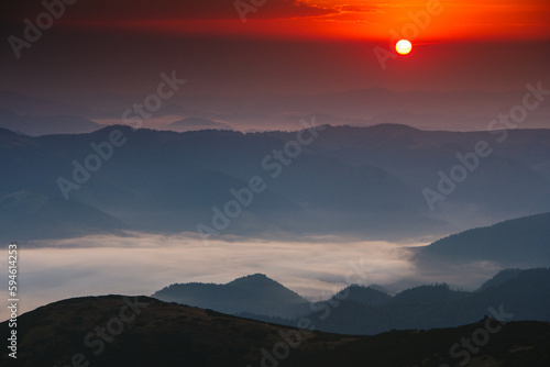 Beautiful landscape in the mountains at sunrise. Fog in the valley. View of a mountain valley in a early morning with fog between hills.
