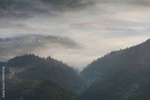 View of a mountains valley in a early morning with fog between hills.