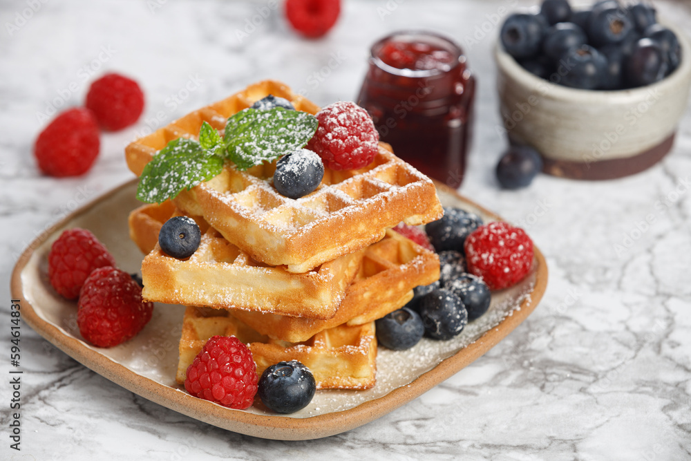 Waffles with berries in plate on grey table Waffles with berries in plate on grey table