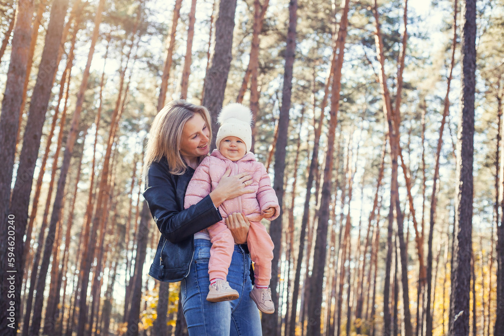 mother and little daughter are walking in a pine forest