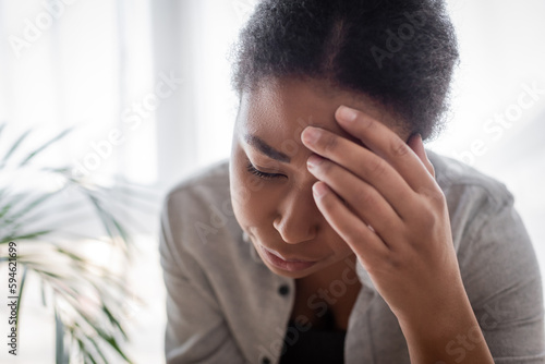 Young multiracial woman suffering from headache at home.