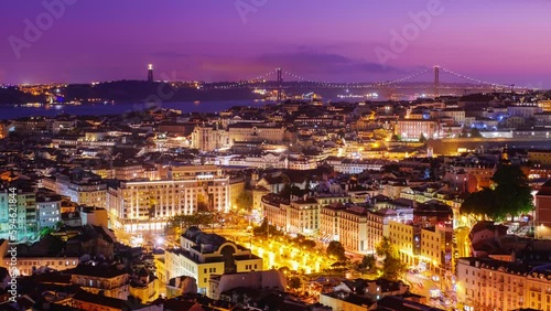 Time-lapse of Lisbon famous view from Miradouro da Senhora do Monte tourist viewpoint over Alfama old city district, 25th of April Bridge in the evening twilight. Lisbon, Portugal. Zoom out effect photo