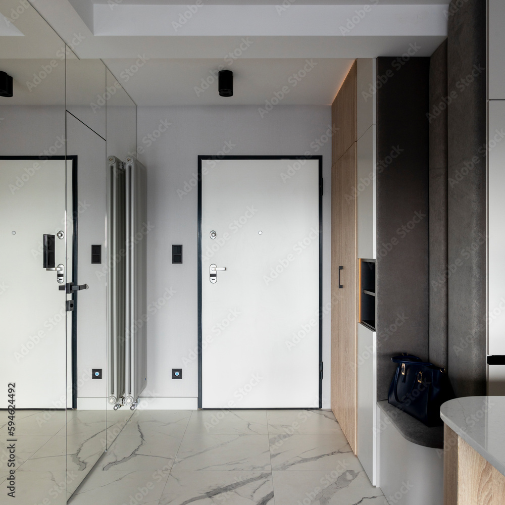 Minimalist composition of vestibule with white door, marble tiles