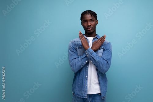 stylish african man with afro curls showing denial gesture on blue background with copy space