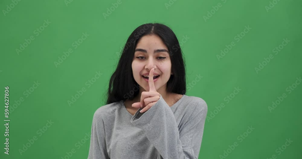 Happy woman keeps index finger on lips makes silence gesture Happy woman keeps index finger on lips makes silence gesture