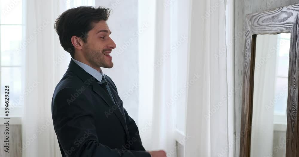 Profile of handsome businessman getting ready by adjusting necktie in front of a mirror Profile of handsome businessman getting ready by adjusting necktie in front of a mirror
